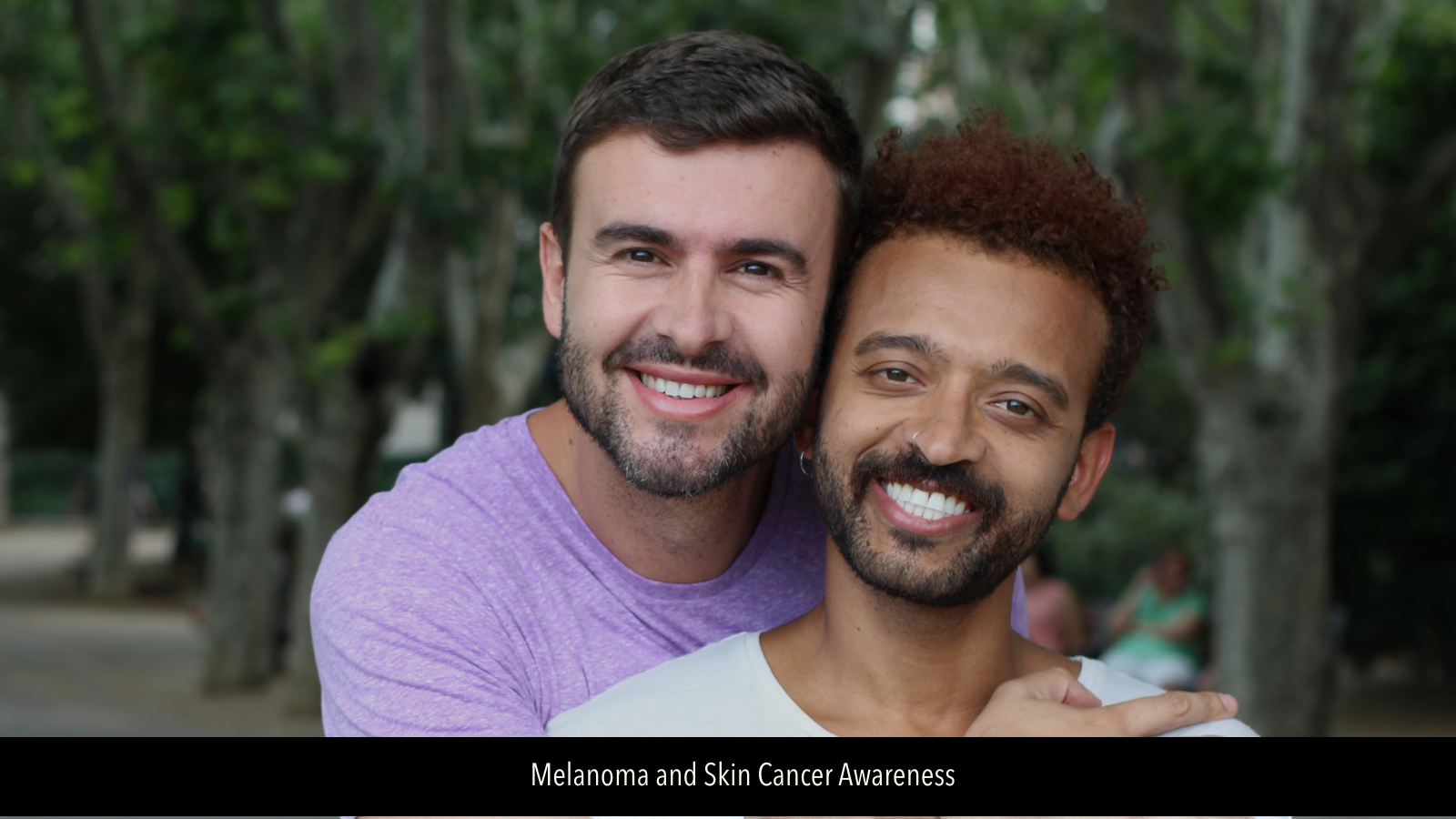Image of male gay couple in an embrace and smiling at camera